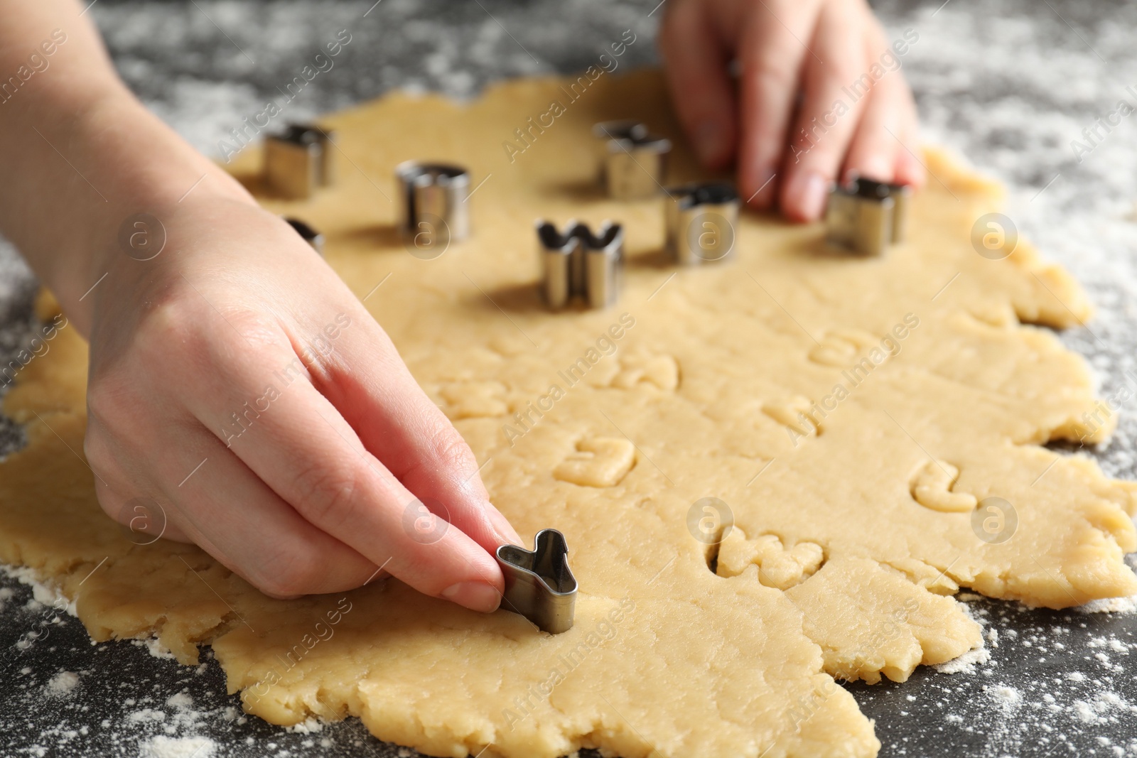 Photo of Shortcrust pastry. Woman making cookies with cutter at grey table, closeup