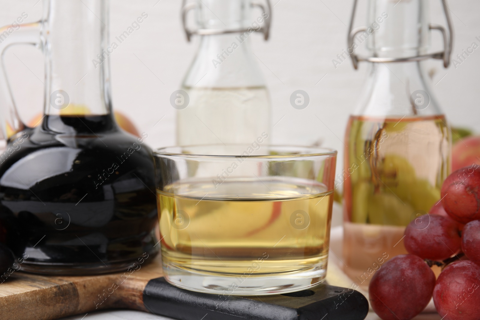 Photo of Different types of vinegar and grapes on table