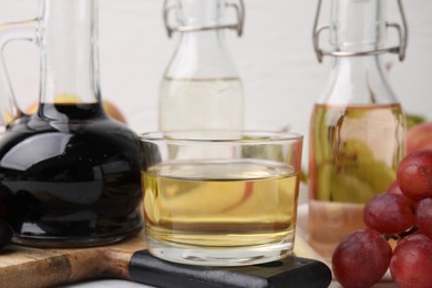 Photo of Different types of vinegar and grapes on table