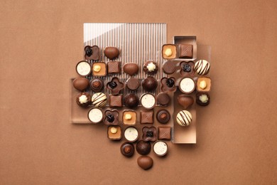 Photo of Heart made with delicious chocolate candies on brown background, top view