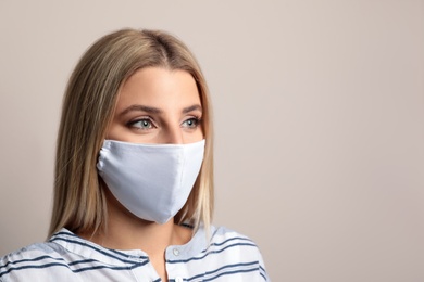 Young woman in protective face mask on beige background. Space for text