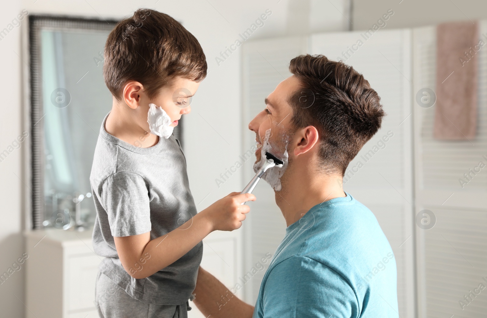 Photo of Little son shaving his dad in bathroom