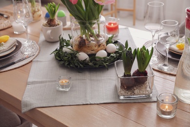 Beautiful Easter table setting with burning candles indoors