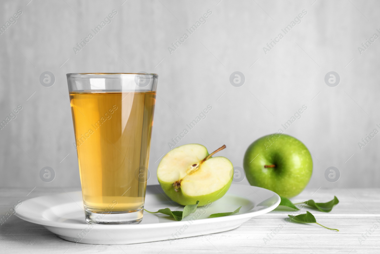 Photo of Glass of fresh apple juice on white wooden table
