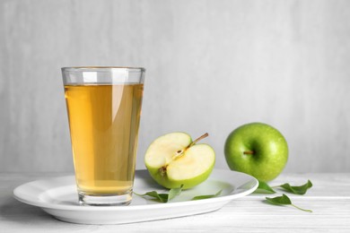 Glass of fresh apple juice on white wooden table