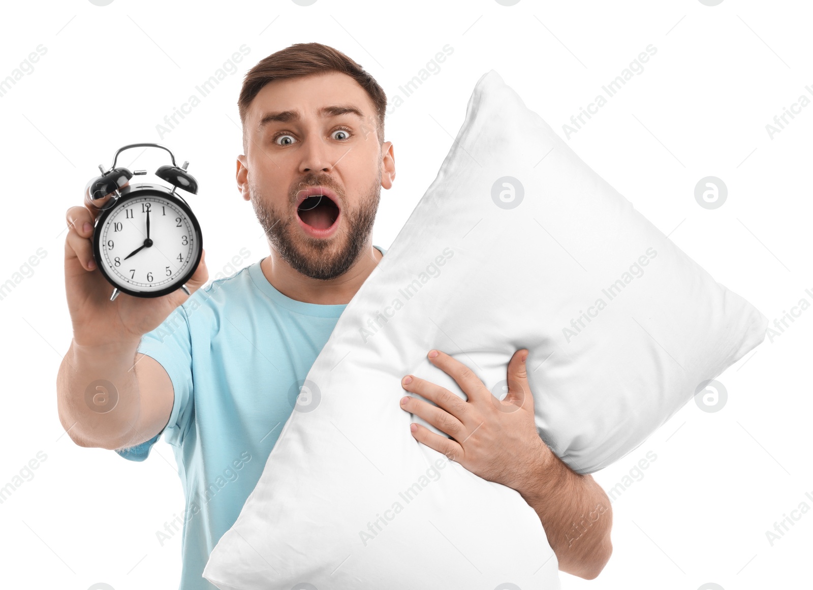 Photo of Emotional overslept man with alarm clock and pillow on white background. Being late concept