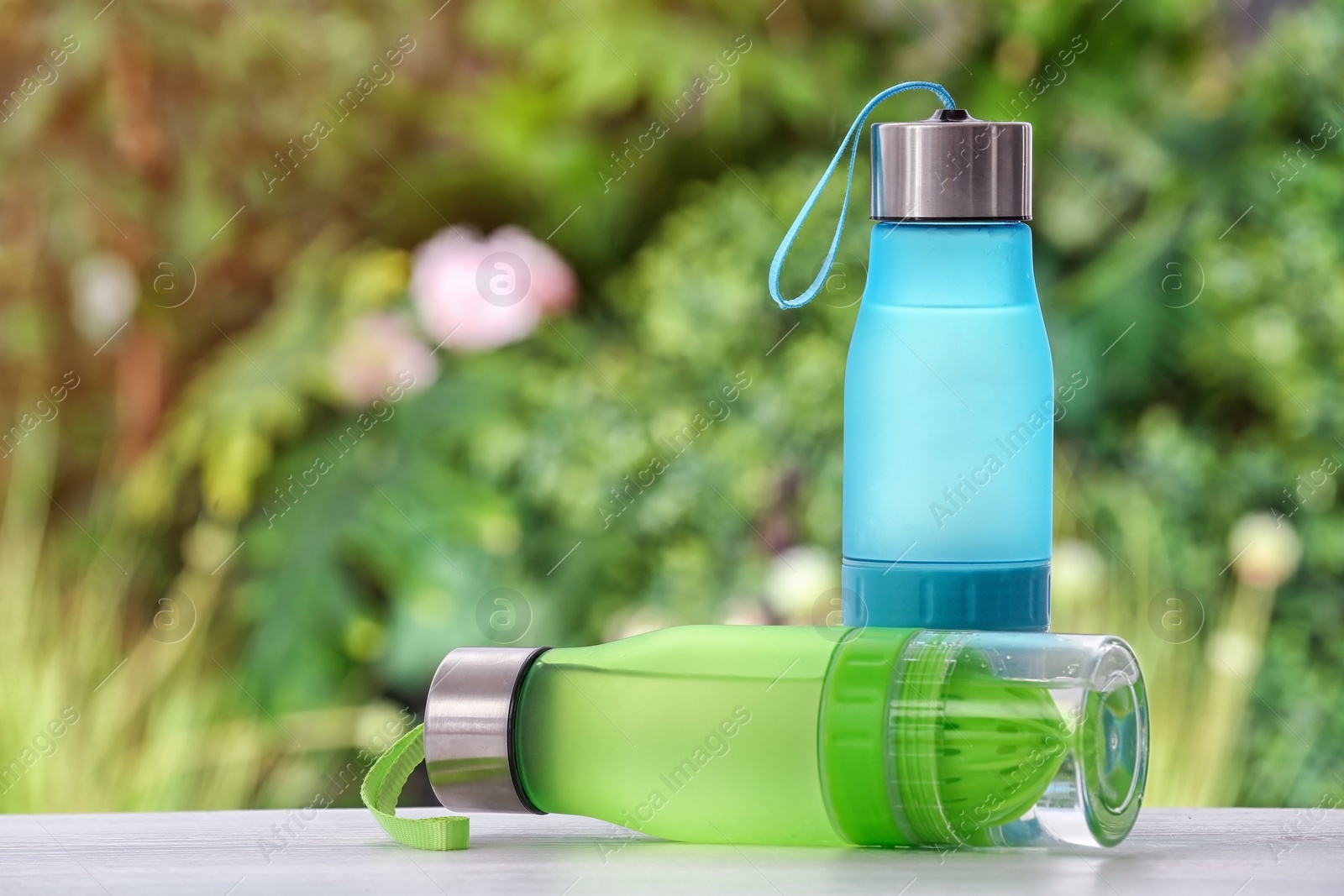 Photo of Sports water bottles on table against blurred background. Space for text