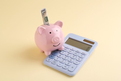 Financial savings. Piggy bank, dollar banknote and calculator on beige background
