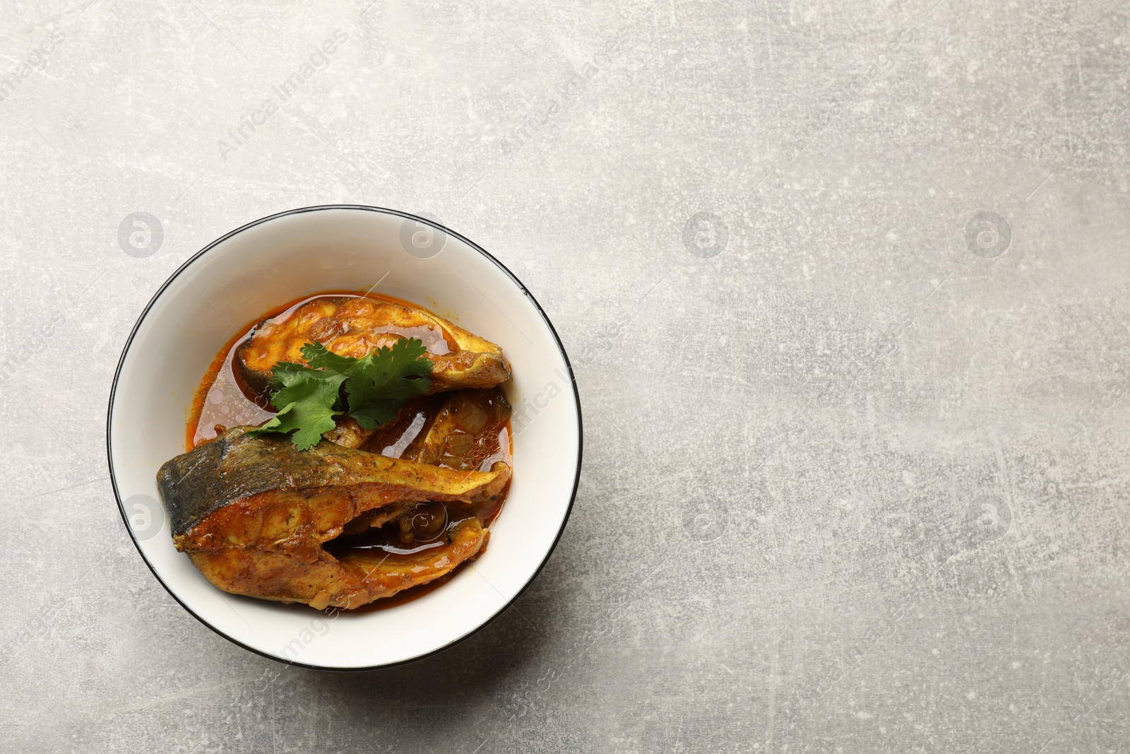 Photo of Tasty fish curry on light grey table, top view. Space for text. Indian cuisine