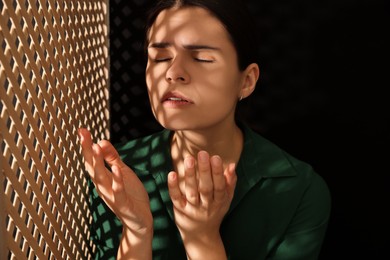 Photo of Woman praying to God during confession in booth