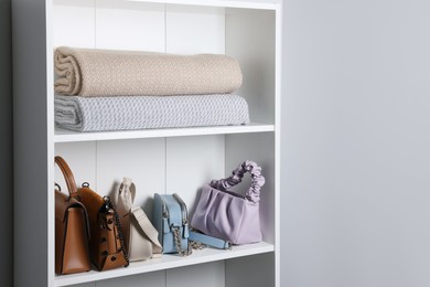 Photo of White shelving unit with rugs and bags in hallway. Interior element