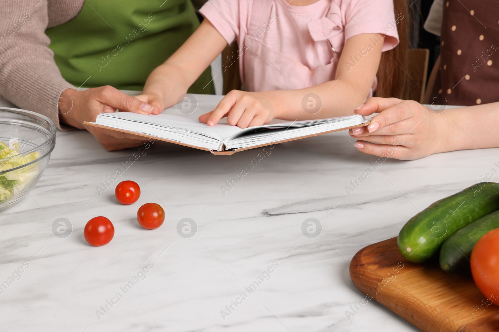 Photo of Family cooking by recipe book in kitchen, closeup