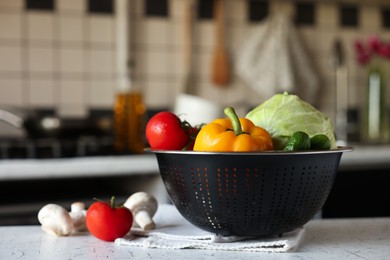 Photo of Metal colander with different wet vegetables on white textured table