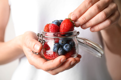 Woman with jar of delicious summer berries, closeup