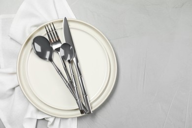 Photo of Stylish setting with elegant cutlery on grey table, top view. Space for text