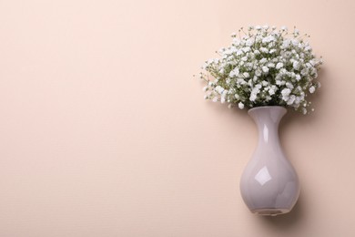 Bouquet of white gypsophila in ceramic vase on beige background, top view. Space for text