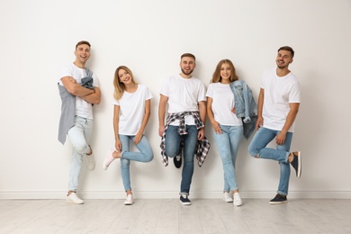 Photo of Group of young people in jeans near light wall