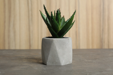 Photo of Artificial plant in flower pot on grey stone table