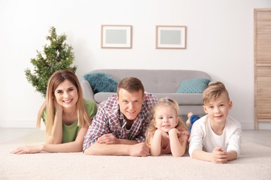 Photo of Happy family lying on cozy carpet at home