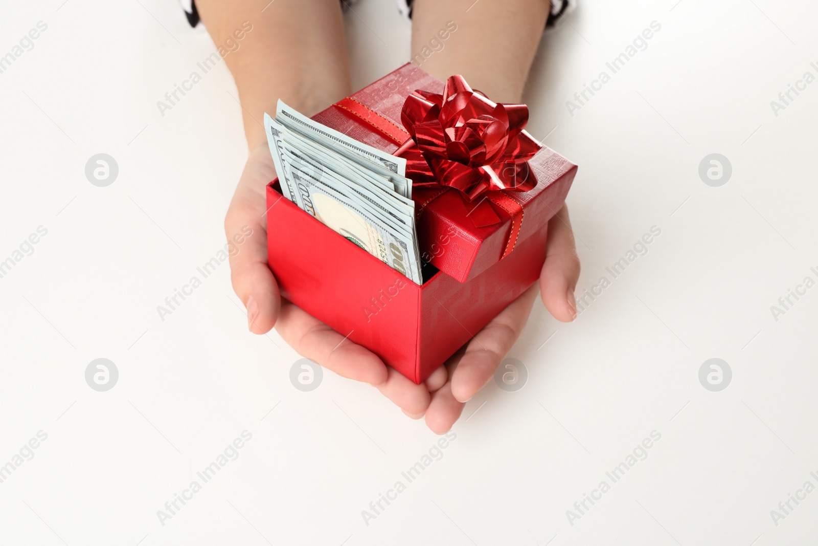 Photo of Woman holding gift box with dollar banknotes on white background, closeup