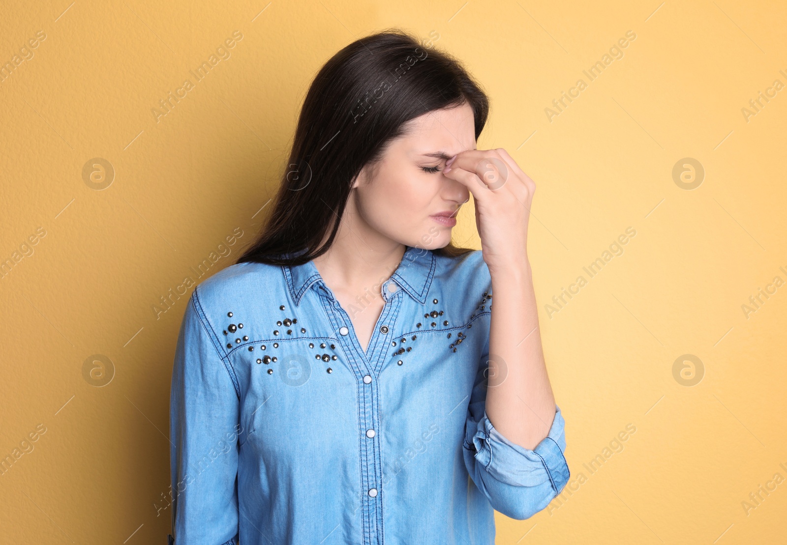 Photo of Young woman suffering from headache on color background