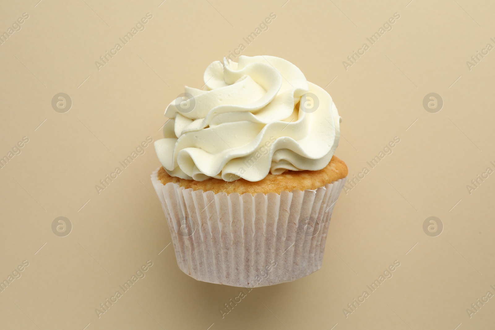 Photo of Tasty vanilla cupcake with cream on beige background, top view