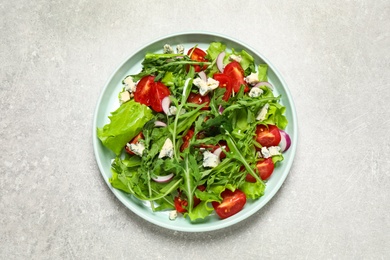 Delicious salad with arugula and tomatoes on grey table, top view