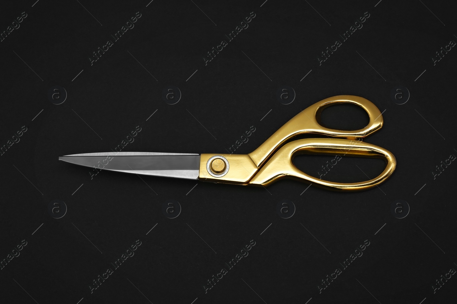 Photo of Gold tailor scissors on black background, top view