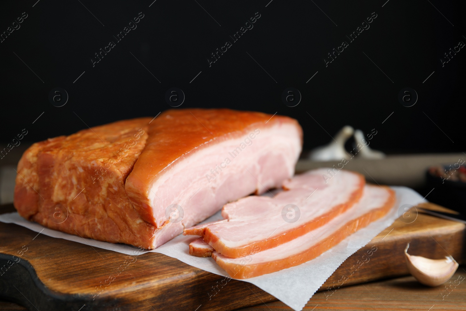 Photo of Delicious smoked bacon and garlic on wooden table, closeup