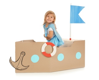 Photo of Cute little girl playing with cardboard ship on white background