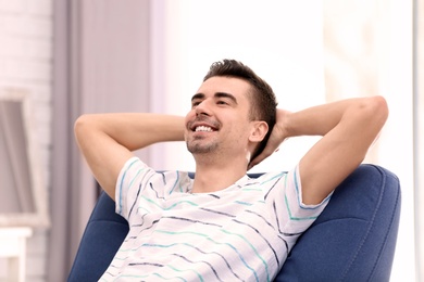 Photo of Young man sitting in armchair at home