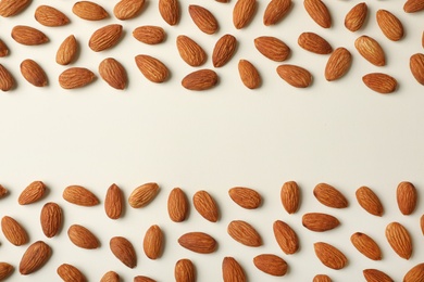 Photo of Composition with organic almond nuts and space for text on light background, top view