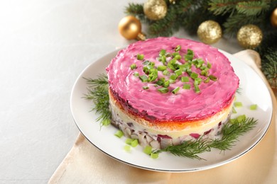 Photo of Herring under fur coat salad and Christmas decor on light grey table, space for text. Traditional Russian dish