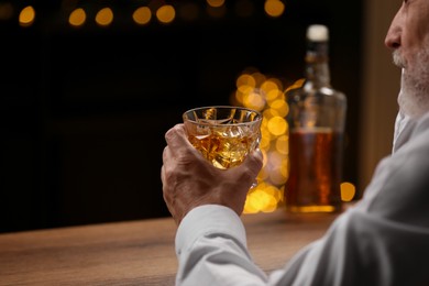 Photo of Senior man with glass of whiskey at bar counter, closeup. Space for text