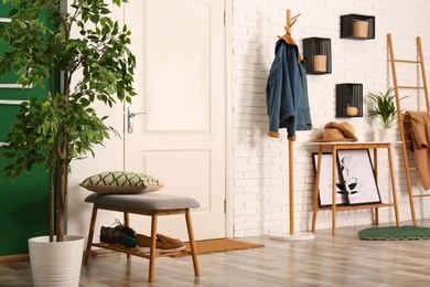 Photo of Stylish hallway interior with shoe storage bench and clothes on hanger stand