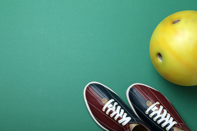 Photo of Bowling ball and shoes on green background, flat lay. Space for text