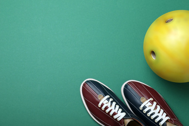 Bowling ball and shoes on green background, flat lay. Space for text