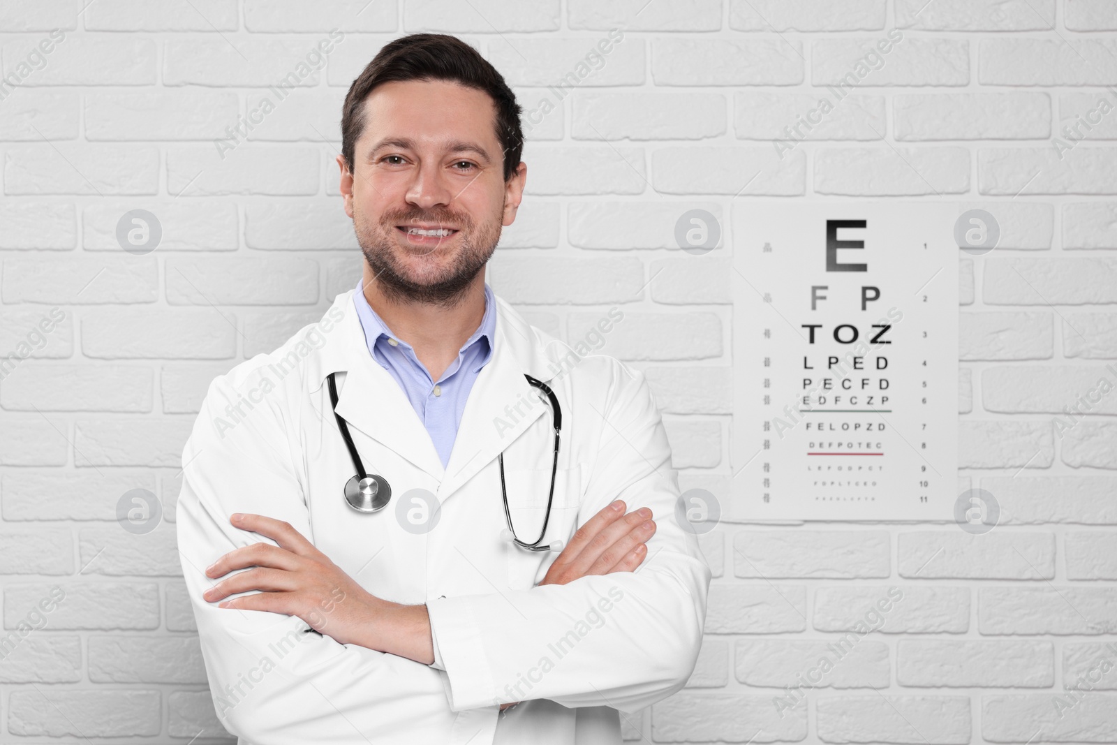 Photo of Ophthalmologist near vision test chart on white brick wall