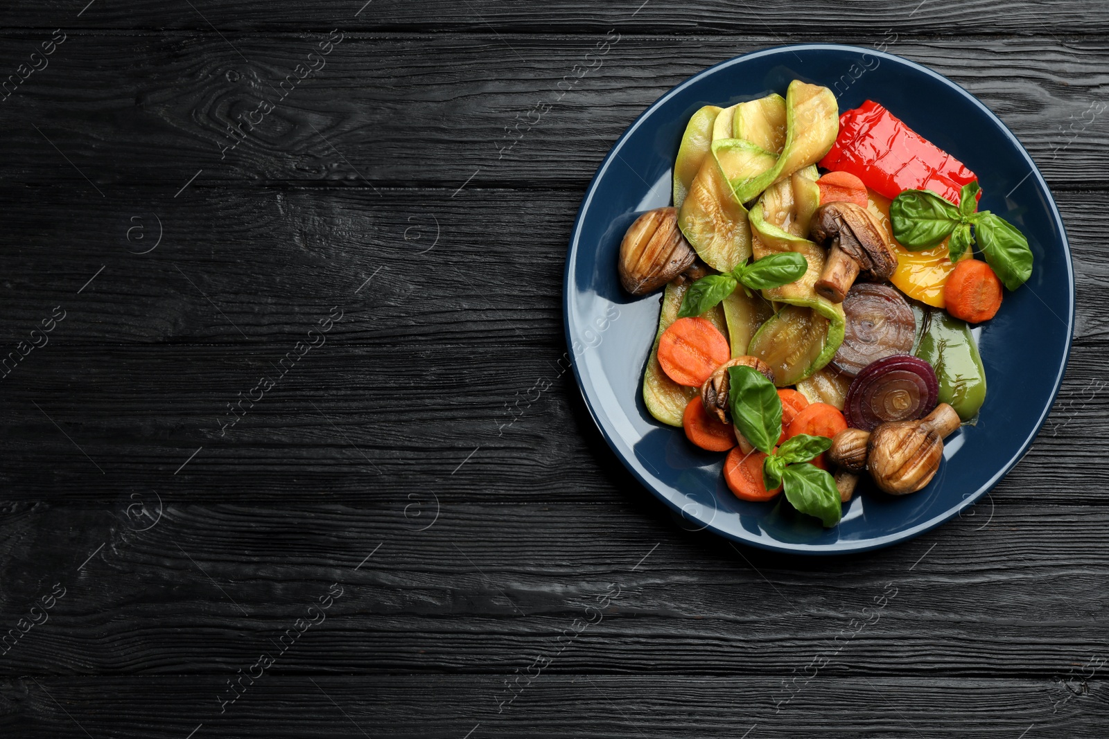 Photo of Delicious grilled vegetables on black wooden table, top view. Space for text