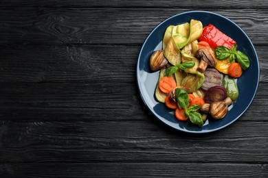 Delicious grilled vegetables on black wooden table, top view. Space for text