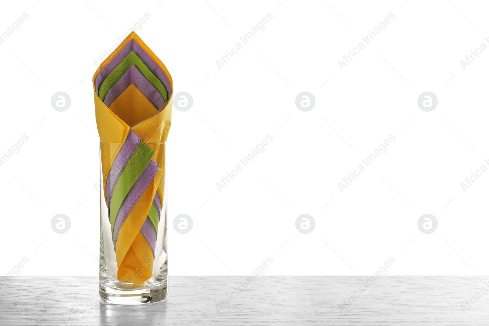 Photo of Glass with paper napkins on table against white background. Space for text