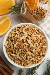 Photo of Bowl of dried orange zest seasoning, fresh fruit and cinnamon on white marble table, flat lay