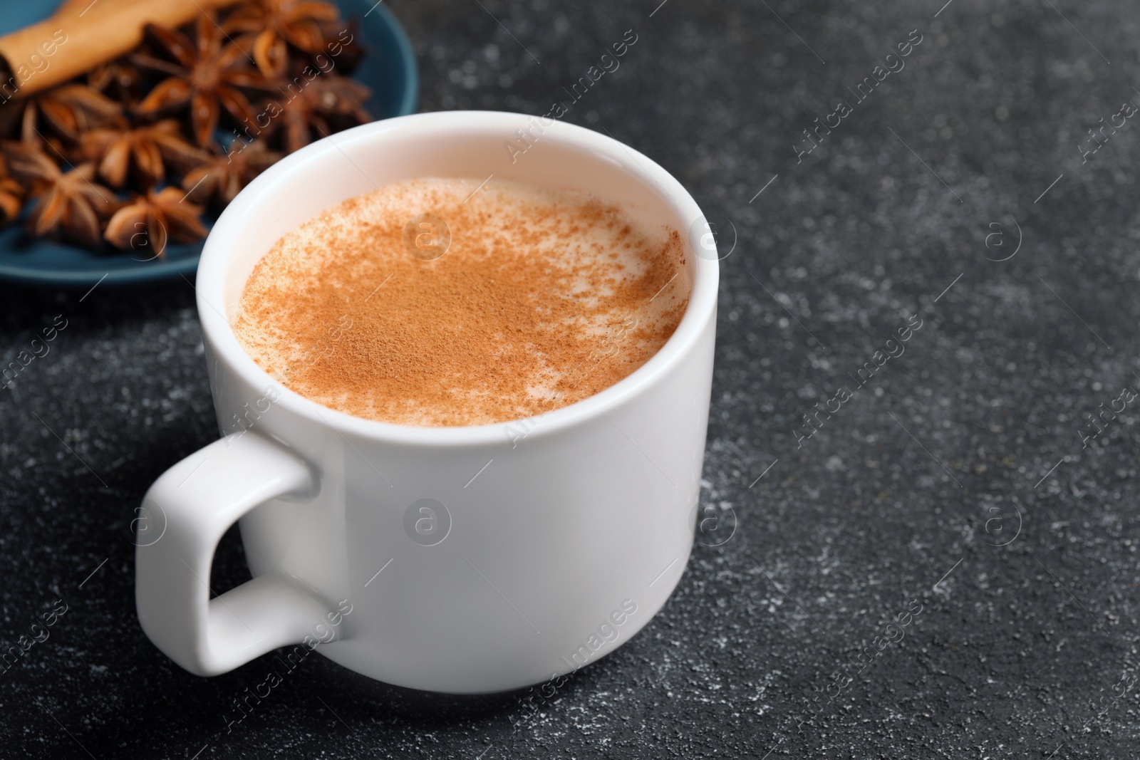 Photo of Delicious eggnog with anise and cinnamon on grey table. Space for text