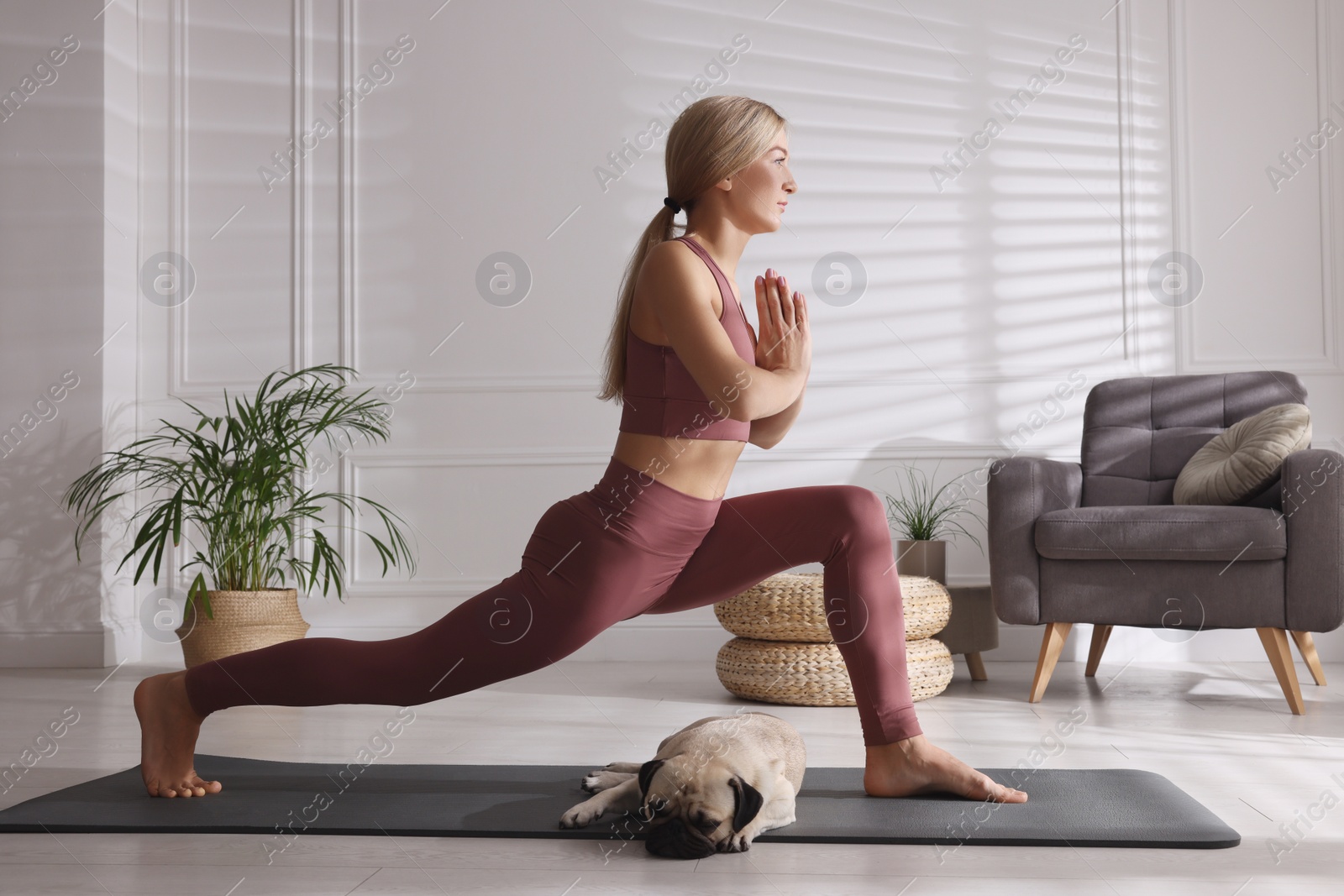 Photo of Beautiful woman with dog practicing yoga at home