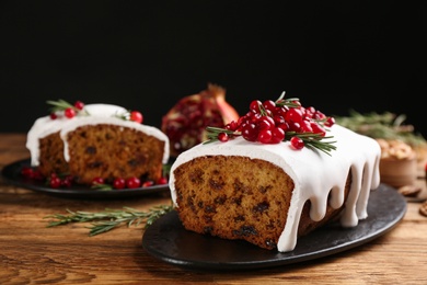Photo of Traditional classic Christmas cake decorated with cranberries, pomegranate seeds and rosemary on wooden table