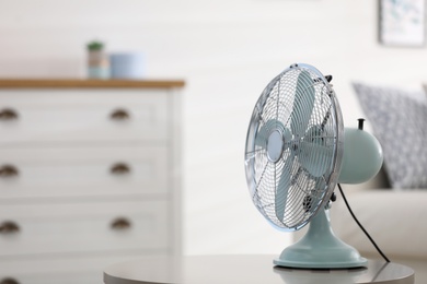 Photo of Modern electric fan on white table indoors. Space for text