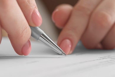 Photo of Woman signing document with pen, closeup view