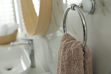 Photo of Holder with clean towel on light wall in bathroom, closeup