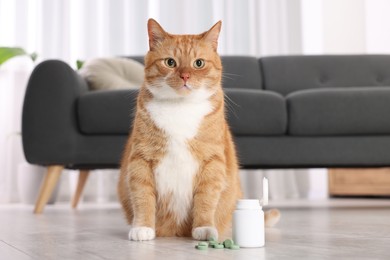 Photo of Cute ginger cat and vitamin pills indoors