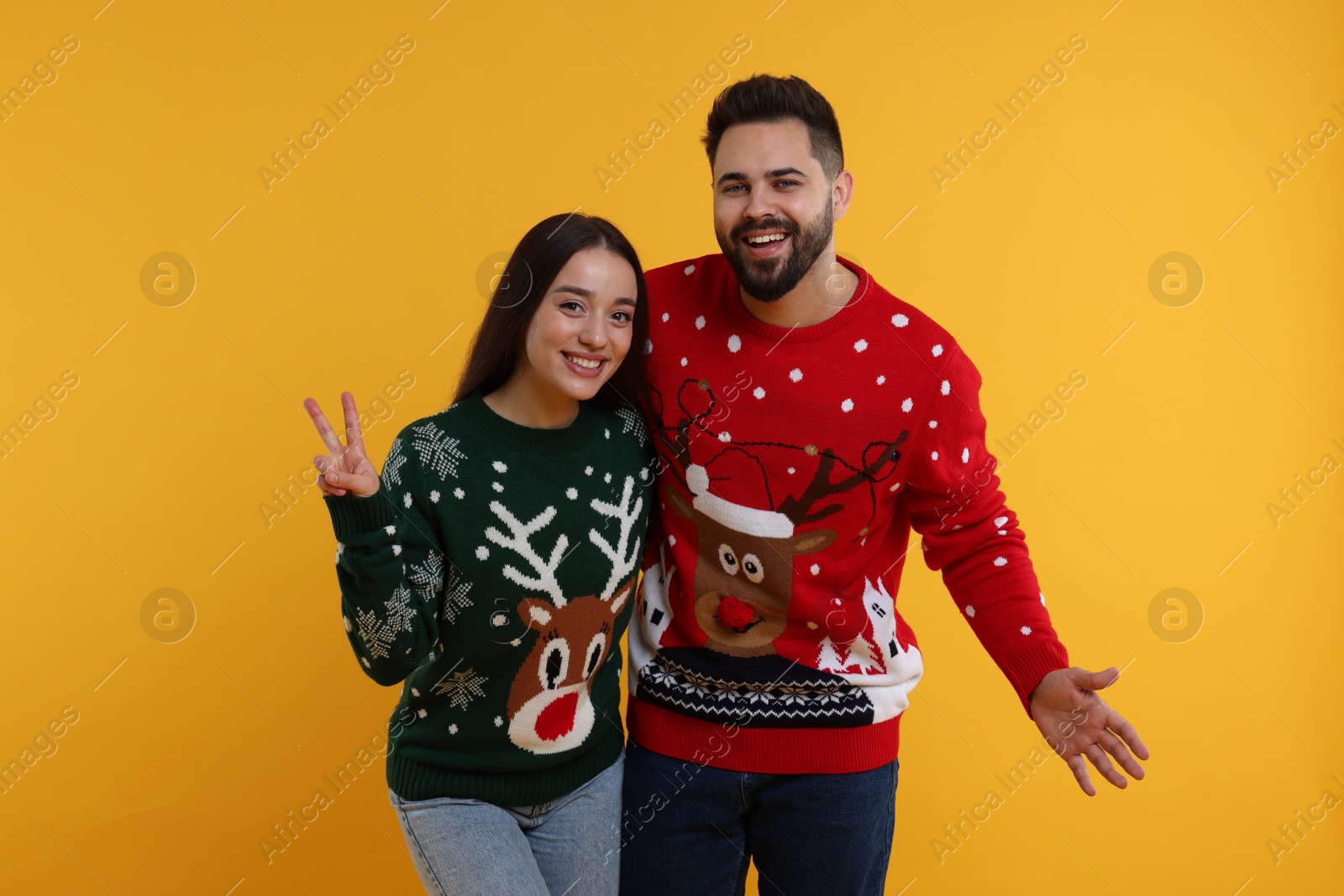 Photo of Happy young couple in Christmas sweaters on orange background